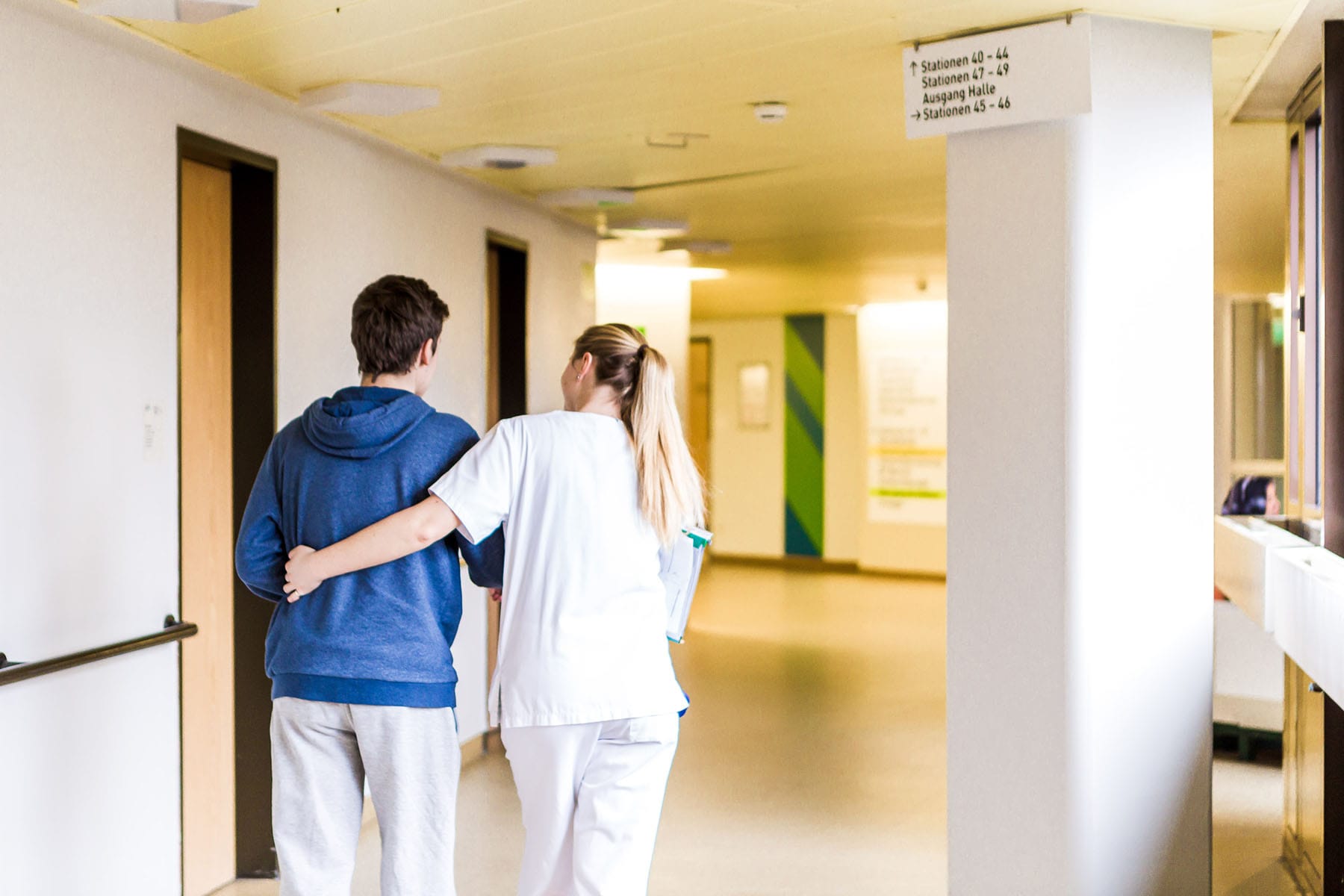 Eine Krankenschwester stützt einen Patienten beim Gehen