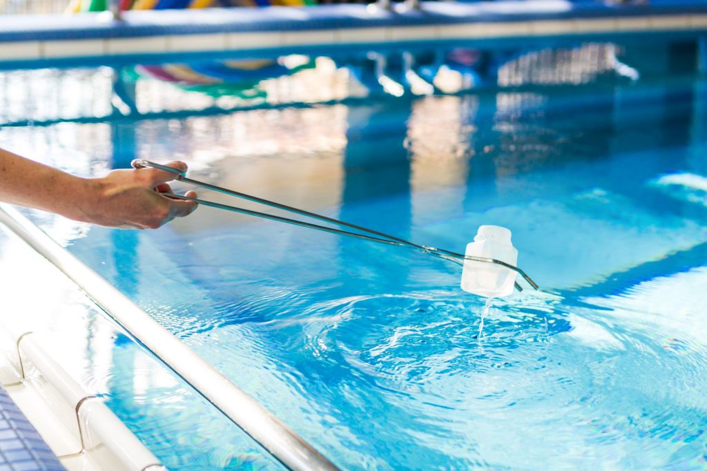 Entnahme einer Wasserprobe mittels eines Bechers und einer Zange im Schimmbad des Klinikums Ingolstadt