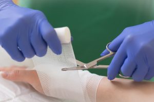 Eine Pflegekraft legt einer Patientin einen Verband am Handgelenk an