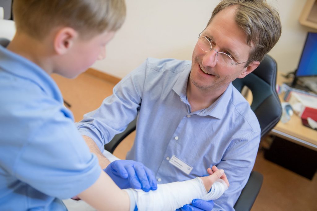 Dr. Bahr legt einem Jungen einen Verband an