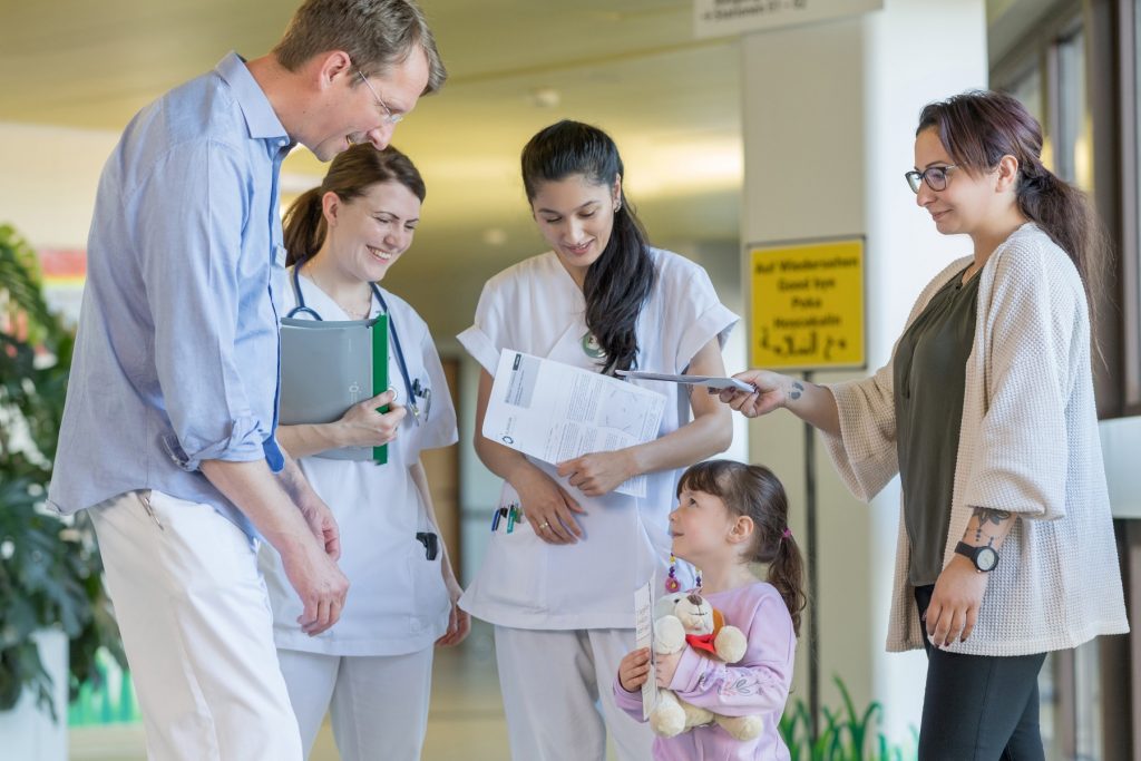 Dr. Bahr und die Stationsschwestern verabschieden ein Kind und seine Mutter
