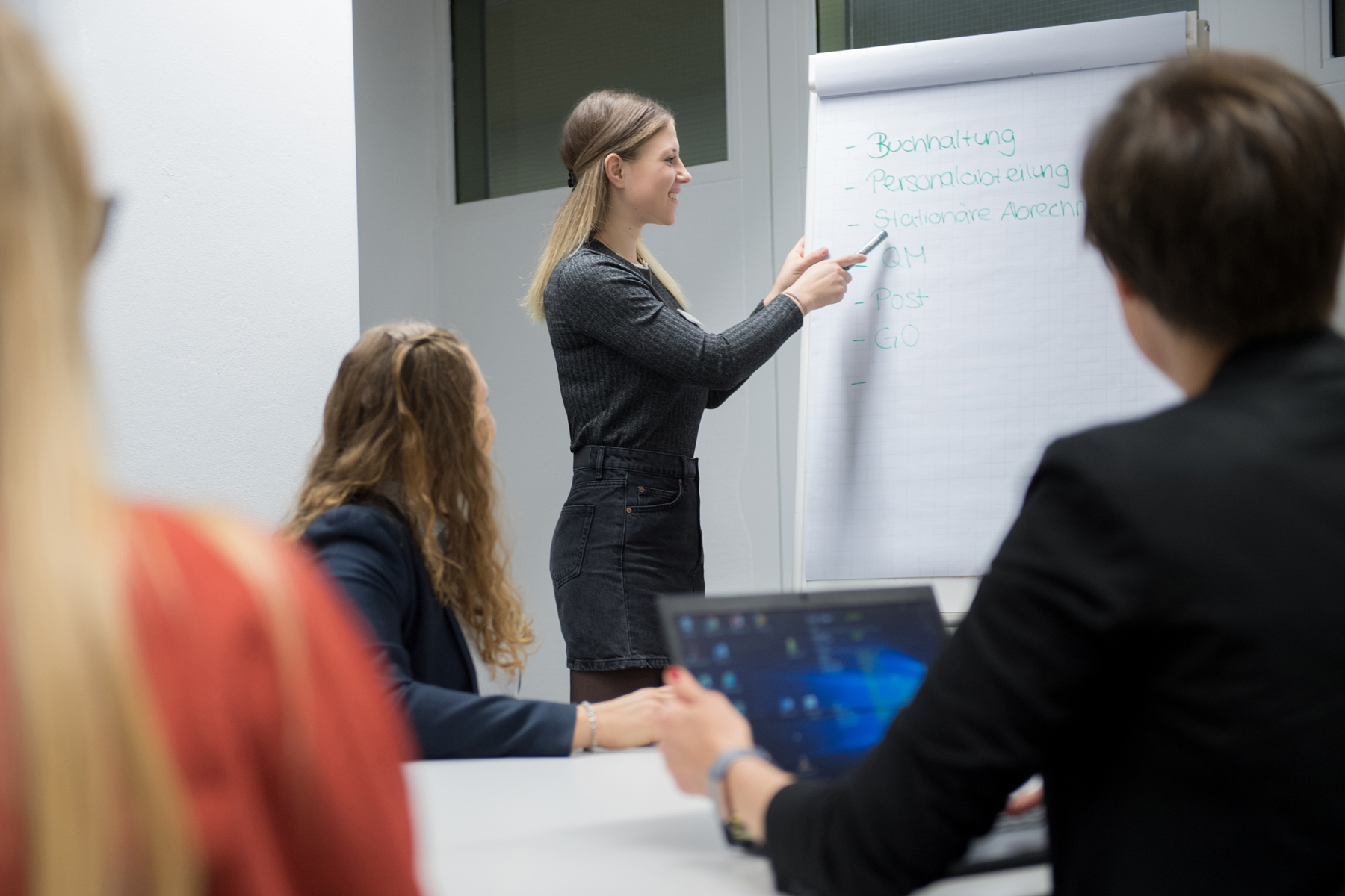 Eine Auszubildende erklärt verschiedene Fachbegriffe am Flipchart.