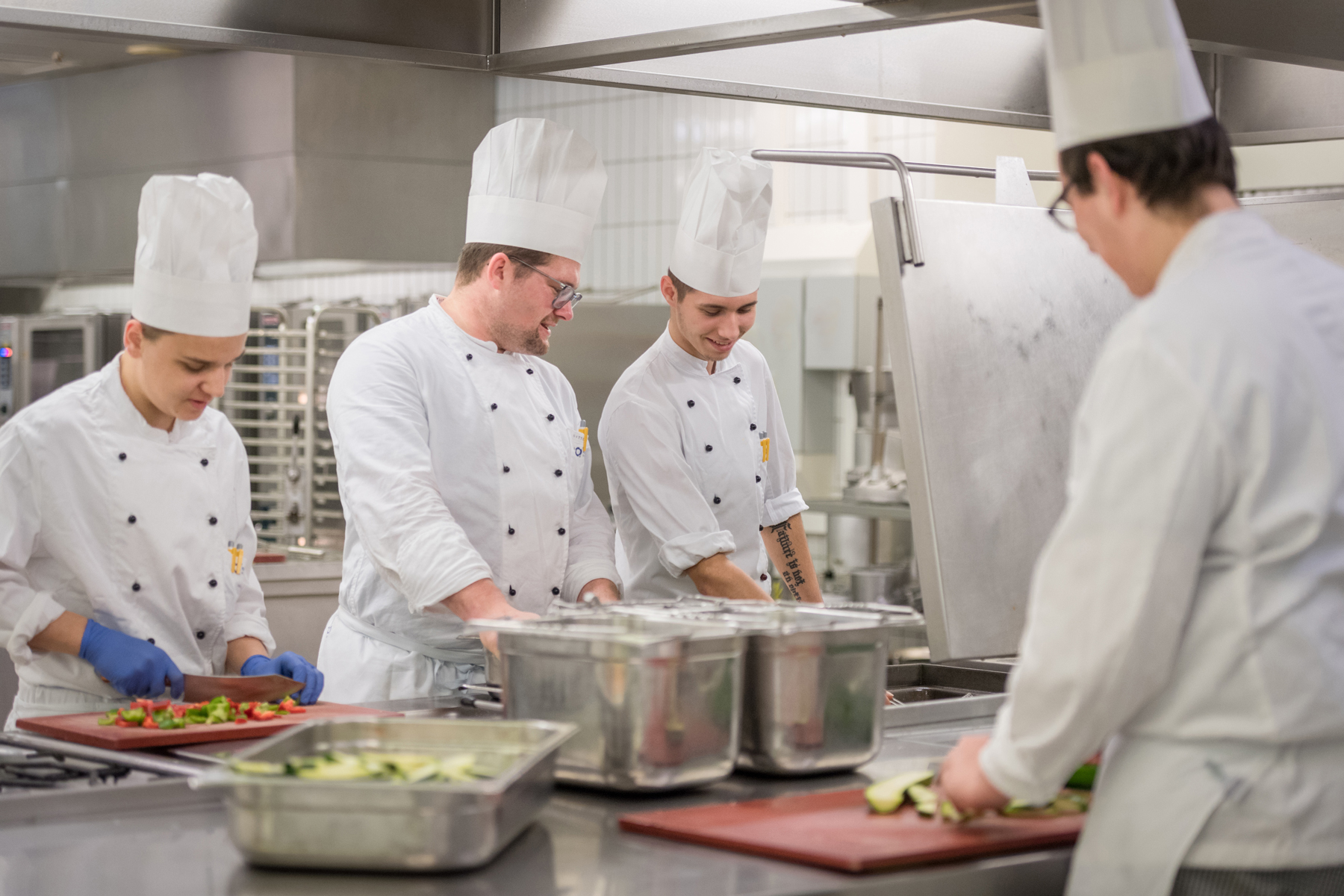 Ein Koch des Klinikums Ingolstadt erklärt einem Azubis, wie man Paprika richtig schneidet
