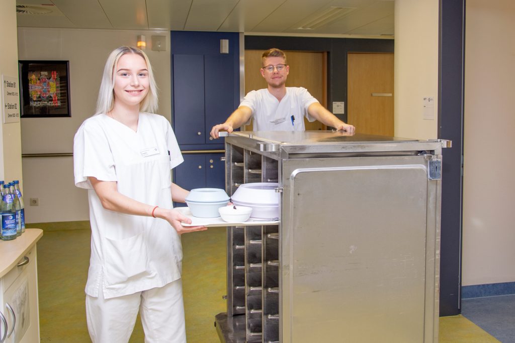 Zwei Bufdis im Klinikum Ingolstadt verteilen Essen auf Station.