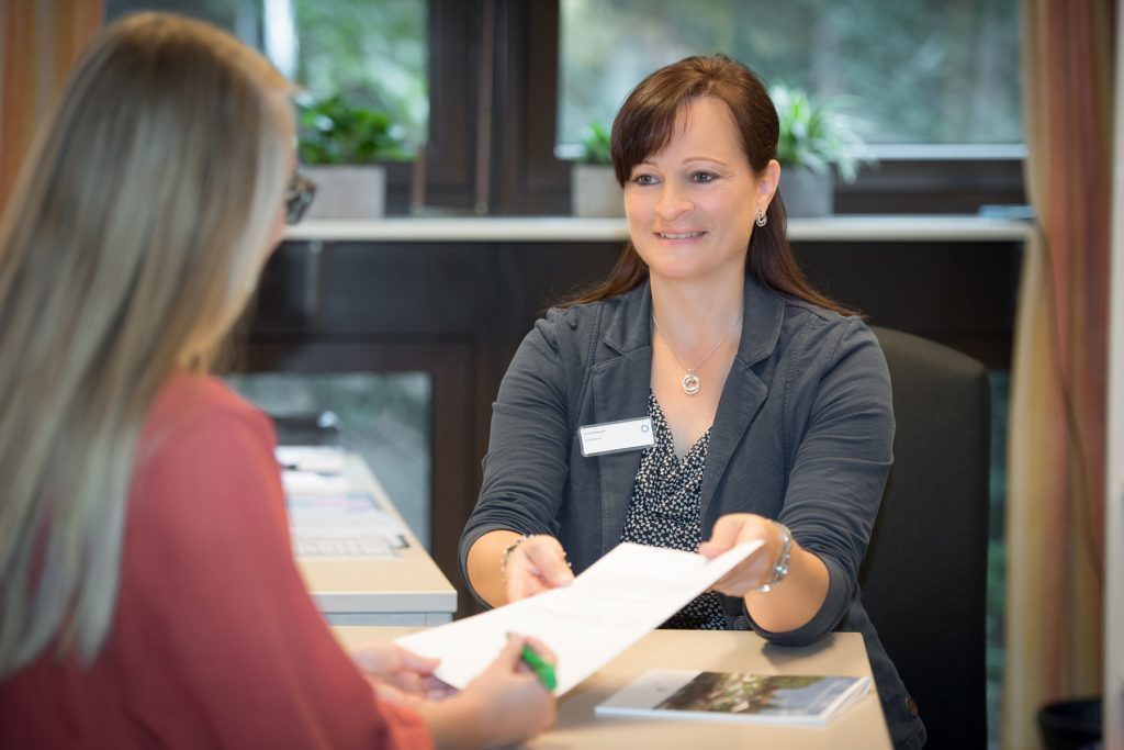 Eine Mitarbeiterin des Sozialdienstes im Klinikum Ingolstadt erklärt eine Patientin wie man das Dokument richtig ausfüllt.