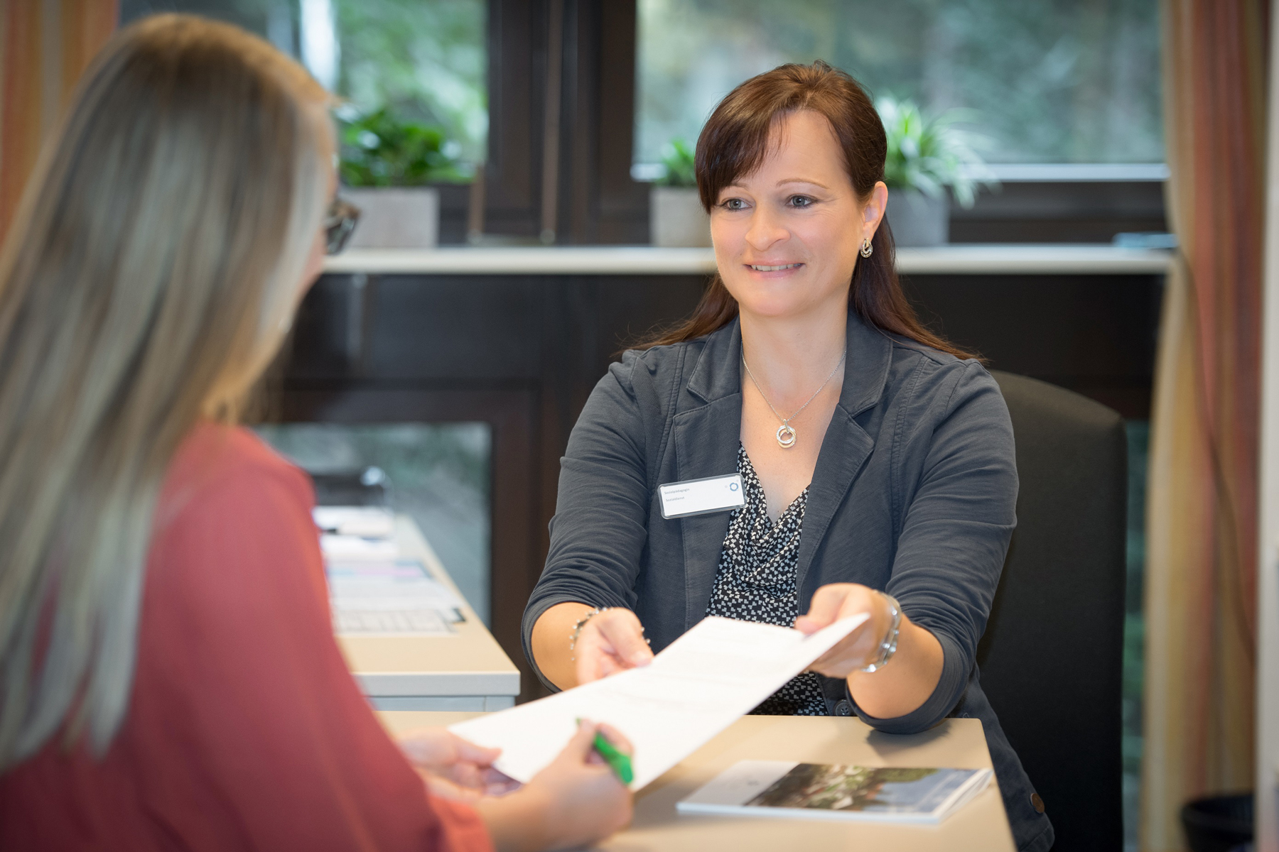 Eine Mitarbeiterin des Sozialdienstes im Klinikum Ingolstadt erklärt eine Patientin wie man das Dokument richtig ausfüllt.