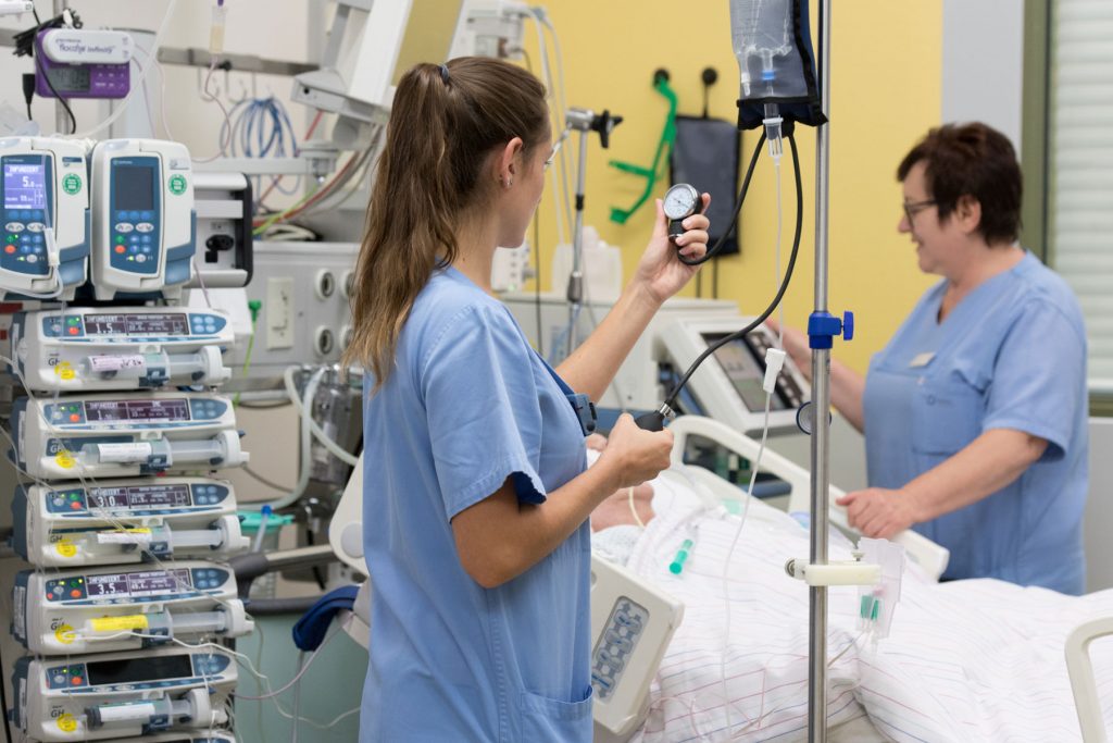 Eine Pflegefachkraft kontrolliert auf der Intensivstation die Vitalwerte eines Patienten.