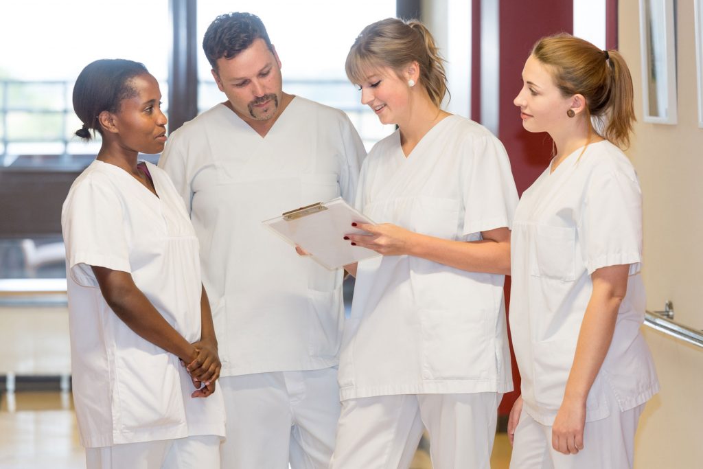 Vier Pflegekräfte sehen sich die Dokumentation zu einem Patienten an.