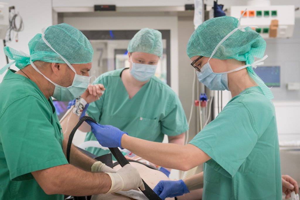 Zwei Pflegekräfte fixieren im OP einen Patienten
